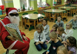 Dzieci z grupy 5 słuchające czytającego Mikołaja